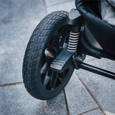 Close-up of the Chicco Corso LE ClearTex Modular Travel System wheel, showcasing its tread pattern and suspension system.