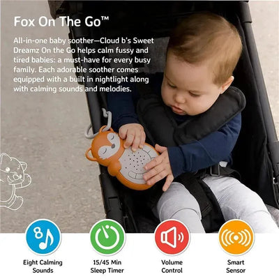 A baby sitting in a stroller holds the Cloud B Sweet Dreamz On The Go, a fox-shaped soother with buttons for sounds and a timer.