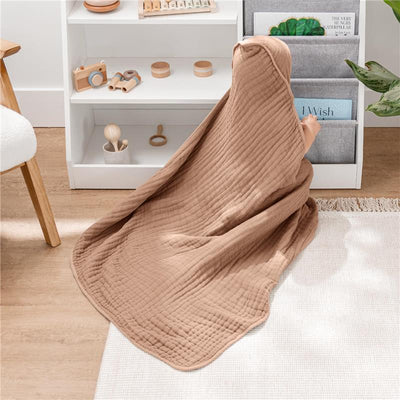 Hooded baby towel in cedar color draped over a child reaching for books on a shelf in a cozy playroom setup.