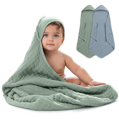 Hooded baby towel set in Pacific Blue and Fern, featuring a baby wearing a green towel, smiling and sitting.
