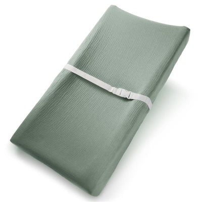 Muslin fitted changing pad cover in soft fern green, secured with a white strap for safety.