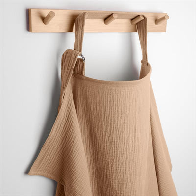 Muslin nursing cover in cedar color, hung on a wooden wall hook, showcasing its soft, textured fabric.