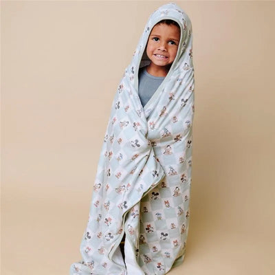 Toddler wrapped in a Mickey Mouse & Friends hooded towel, smiling against a neutral background.