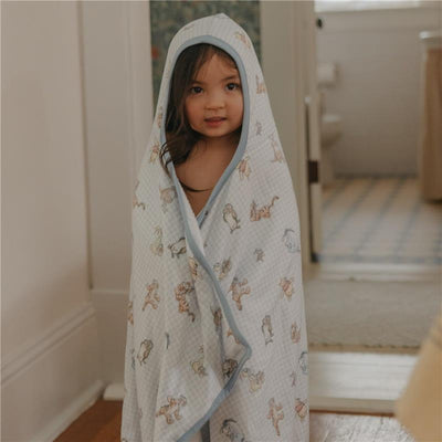 Little girl in a hooded towel featuring Winnie the Pooh and friends, standing in a bathroom.
