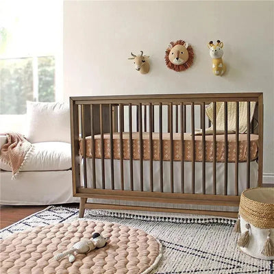 Soft cotton crib mattress sheet in copper dash pattern, fitted on a crib in a stylish nursery with animal wall decor.