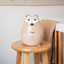 Ultrasonic cool mist humidifier shaped like a fox on a wooden stool, with control settings and cozy blanket in the background.