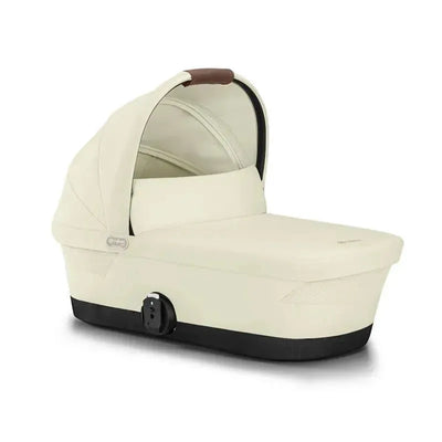 Cybex Gazelle S Cot in Seashell Beige, featuring a sleek design with a soft beige fabric and a brown handle.
