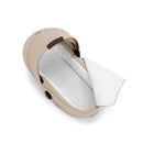 Foldable Cybex Gazelle S Cot in almond beige with a white interior, featuring a partially open cover.