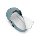 Foldable Cybex Gazelle S Cot in Stormy Blue with a white interior, showcasing the open design and a brown handle.
