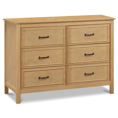 Davinci Charlie 6-drawer baby dresser in honey finish with black metal handles and a smooth top surface.