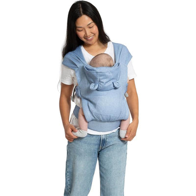 Woman wearing the Delta Legacy Baby Carrier in Chambray, smiling while holding a baby comfortably in the carrier.