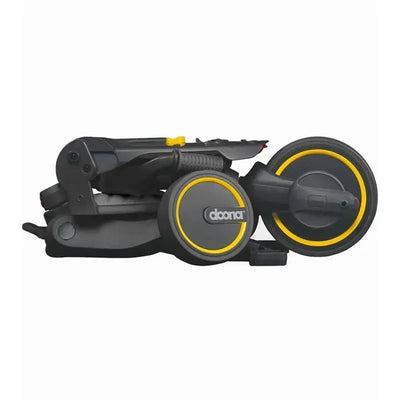 Folded Doona Liki Trike S3 in Grey Hound design, showcasing its compact form and distinct yellow accents on wheels.