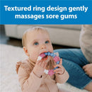 Baby with blue eyes uses a pink/purple Dr. Brown teething ring, which features textured, flower-shaped attachments.