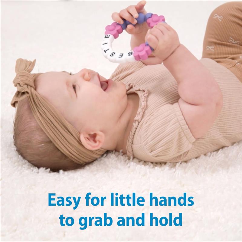 Baby smiling while holding a pink and purple silicone teething ring, designed for easy gripping.
