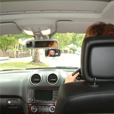 Adjustable baby view mirror reflecting a smiling baby, installed in a car for safe rear seat visibility.