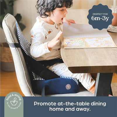 Blue denim striped booster seat designed for children aged 6 months to 3 years, with a child seated at a table.