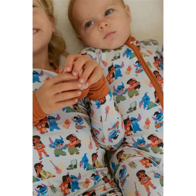 Two children wearing matching Ellie Sue Baby Ohana bamboo pajamas with colorful character prints, holding hands.