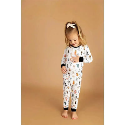 Toddler wearing Ellie Sue bamboo pajamas featuring colorful dog and animal prints, with a beige background.