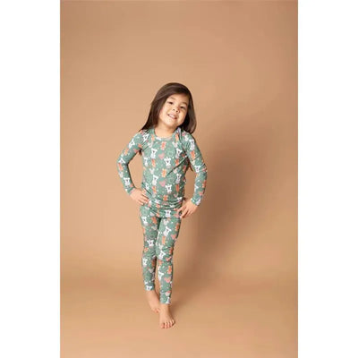 Child wearing Disney Mickey Christmas Magic Pajamas, featuring a green pattern with Mickey and festive designs, smiling.