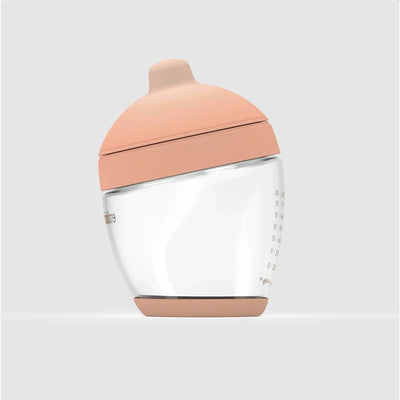 Glass classic baby bottle with a fair-colored nipple, featuring measurement markings on the side.