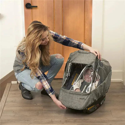 Evenflo Infant Carrier Weather Shield in Gray Melange, featuring a protective cover and a seated infant inside, held by a woman.