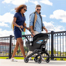Couple walking outdoors, using the Evenflo Shyft Dualride Infant Car Seat & Stroller Combo in Beaufort Black.