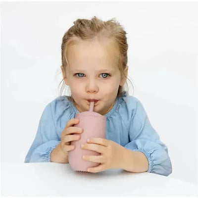 Child sipping from a pewter-colored Ezpz Happy Cup with a straw, wearing a light blue shirt.