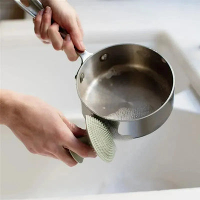 Ezpz Mushroom Sponge in Sage color being used to clean a stainless steel pot with soapy water.