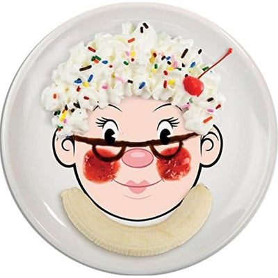 Dinner plate designed with a cartoon face featuring whipped cream, sprinkles, a cherry, and banana slices as food elements.