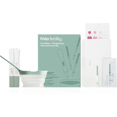 Frida Fertility ovulation and pregnancy test set featuring test strips, a collection cup, and tracking materials.