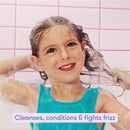 Child washing her hair with the Frida for Kids 2-in-1 Shampoo & Conditioner, displaying a happy expression and bubbles.