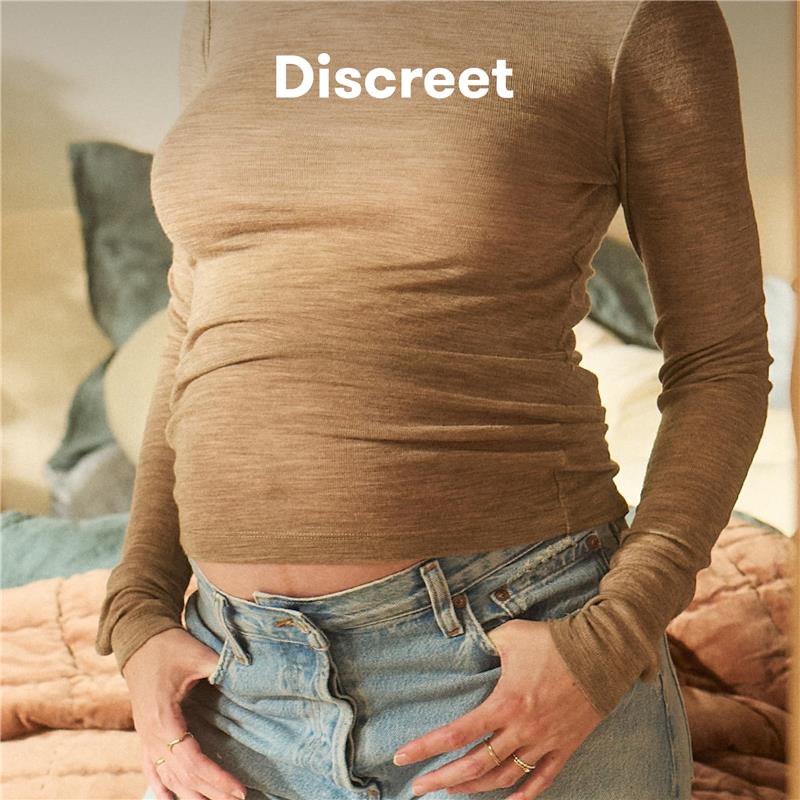 Frida Mom Dual Support Pregnancy Belly Band in clay, worn under a fitted top, emphasizing discreet support for maternity.