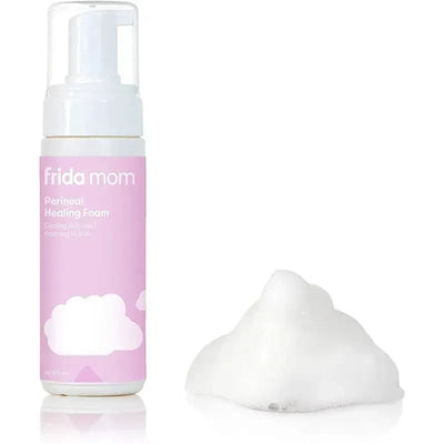 Frida Mom Perineal Healing Foam bottle with pink label and white foam placed beside it, designed for postnatal comfort.