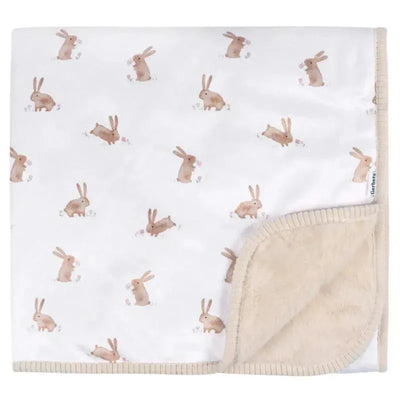 Plush blanket featuring a soft white surface adorned with cute, brown bunny illustrations and a tan plush backing.