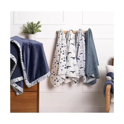 Four flannel blankets in assorted whale and nautical patterns hang on a wooden rack, with a dark blue blanket in the foreground.