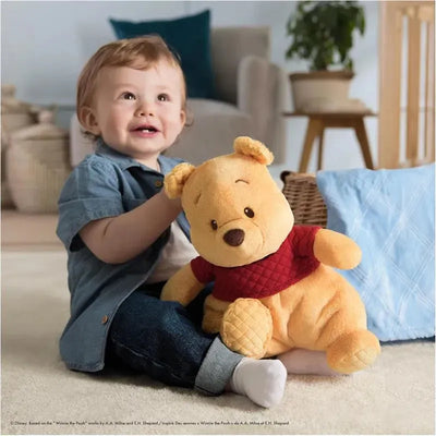 Toddler smiles while holding a large, plush Winnie the Pooh toy, featuring a red shirt and soft fur, in a cozy setting.