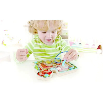 Child playing with the Hape Choo Choo Tracks magnetic wooden maze puzzle, maneuvering a wire through colorful tracks.