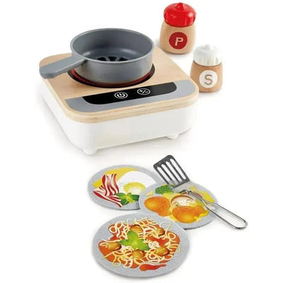 Wooden tabletop stove with a fan, pot, two spice containers, spatula, and three food play mats featuring eggs, bacon, and spaghetti.