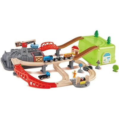 Colorful wooden train set featuring tracks, a crane, toy trains, and buildings for imaginative play.