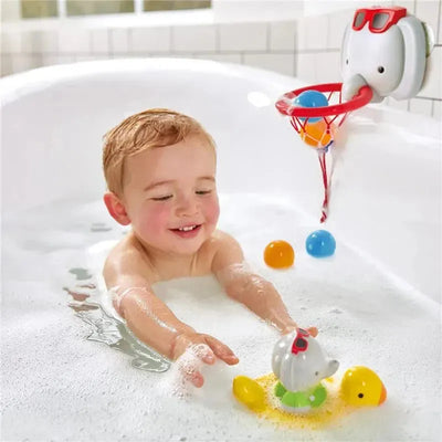 Toddler enjoying bath time, playing with floating toys, including a duck and a spinning elephant basket with colorful balls.