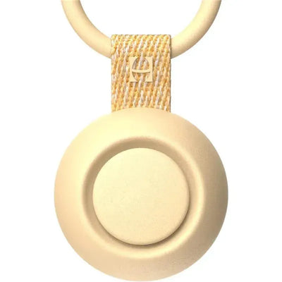 Portable honey-colored sound machine with a circular design and a fabric loop for easy attachment.