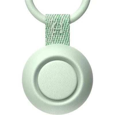 Portable mint green sound machine for babies with a circular design and textured strap for easy attachment.