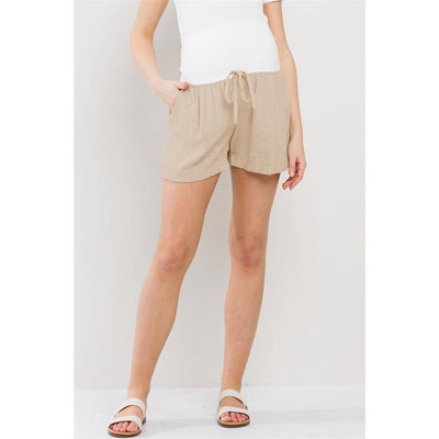 Khaki linen blend maternity shorts with an elastic band, styled with a white top and slip-on sandals.