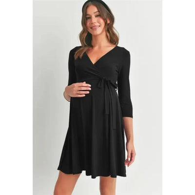 Black surplice quarter sleeve nursing dress with waist tie, worn by a smiling woman cradling her baby bump.