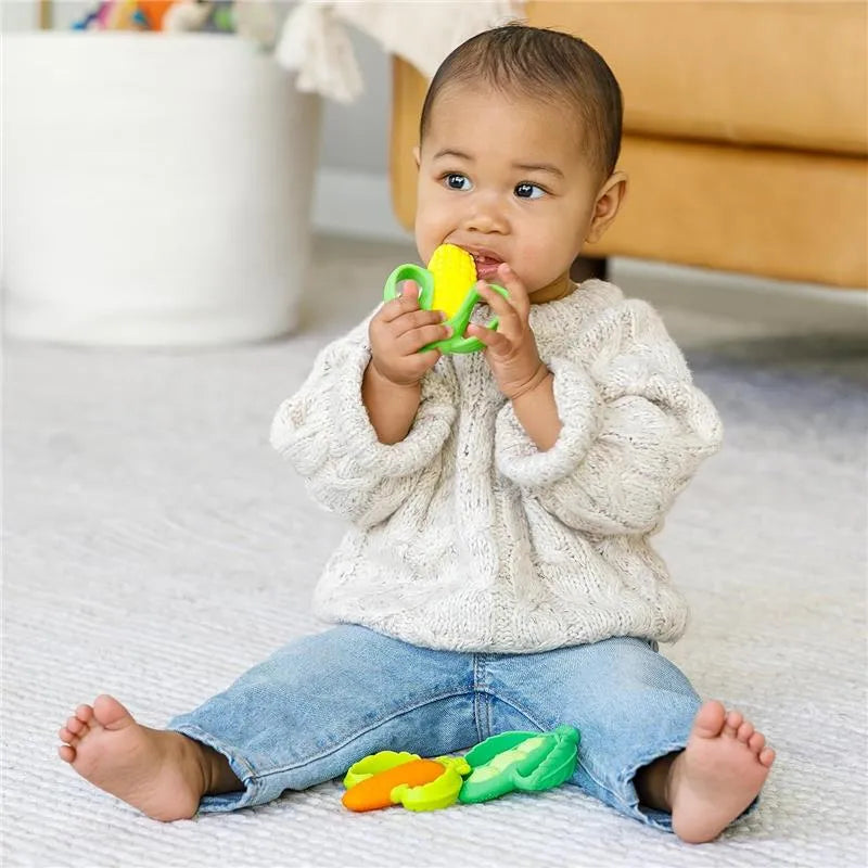 Infantino Farmers Market Teether Gift Set shown with a baby sitting on the floor, chewing a green and yellow corn-shaped teether.