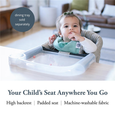 Cream Inglesina Fast Table Chair with a high backrest and padded seat, featuring a toddler comfortably seated with a dining tray.