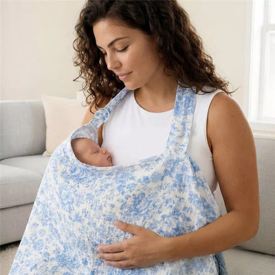 Breastfeeding cover in blue toile pattern being used by a woman to nurse a sleeping baby.