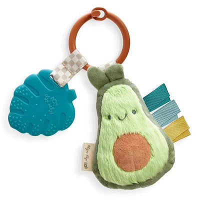 Plush avocado teether with a soft texture, colorful ribbon tags, and a blue teething ring attachment.