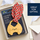 Silicone teether shaped like a smiling pasta with a red tomato-patterned crinkle tie, packaged for gifting.