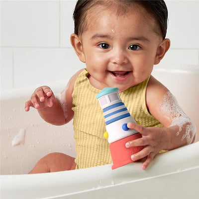 Smiling baby in a bath holds a colorful lighthouse-shaped toy, surrounded by bubbles.